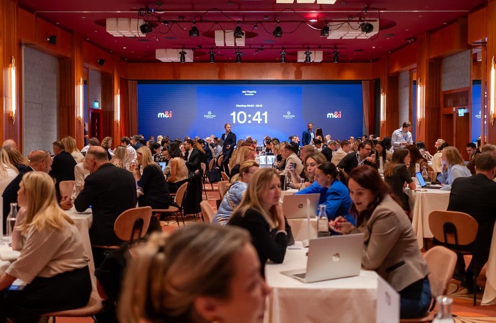 A full meetings hall at an M&I event, the countdown running on the main screen