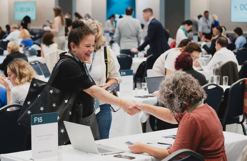 Buyers and suppliers shaking hands across the tables in pre-scheduled meetings